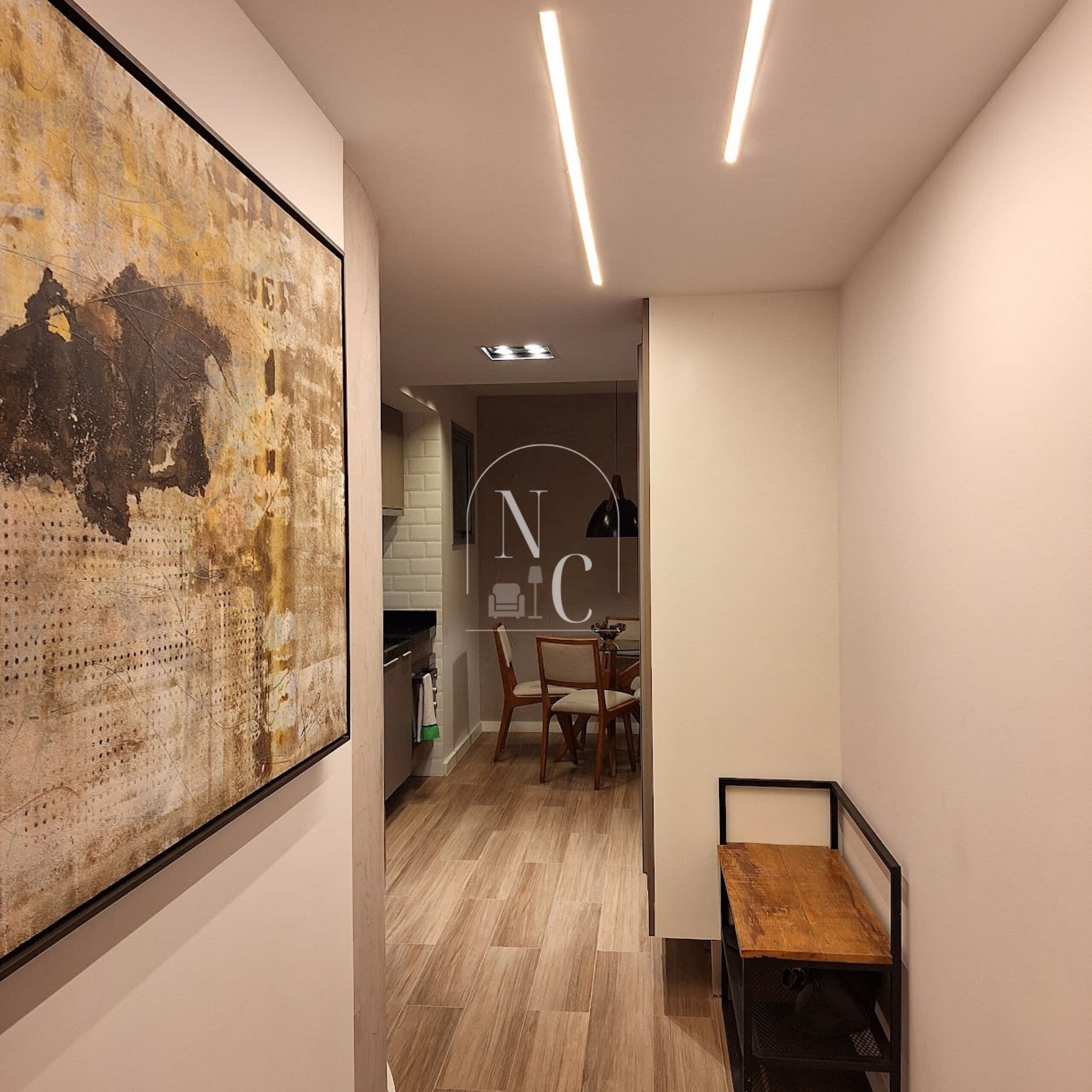 Ein Flur mit Holzboden, eine Essecke mit Stühlen und ein an der Wand befestigtes Kunstwerk.