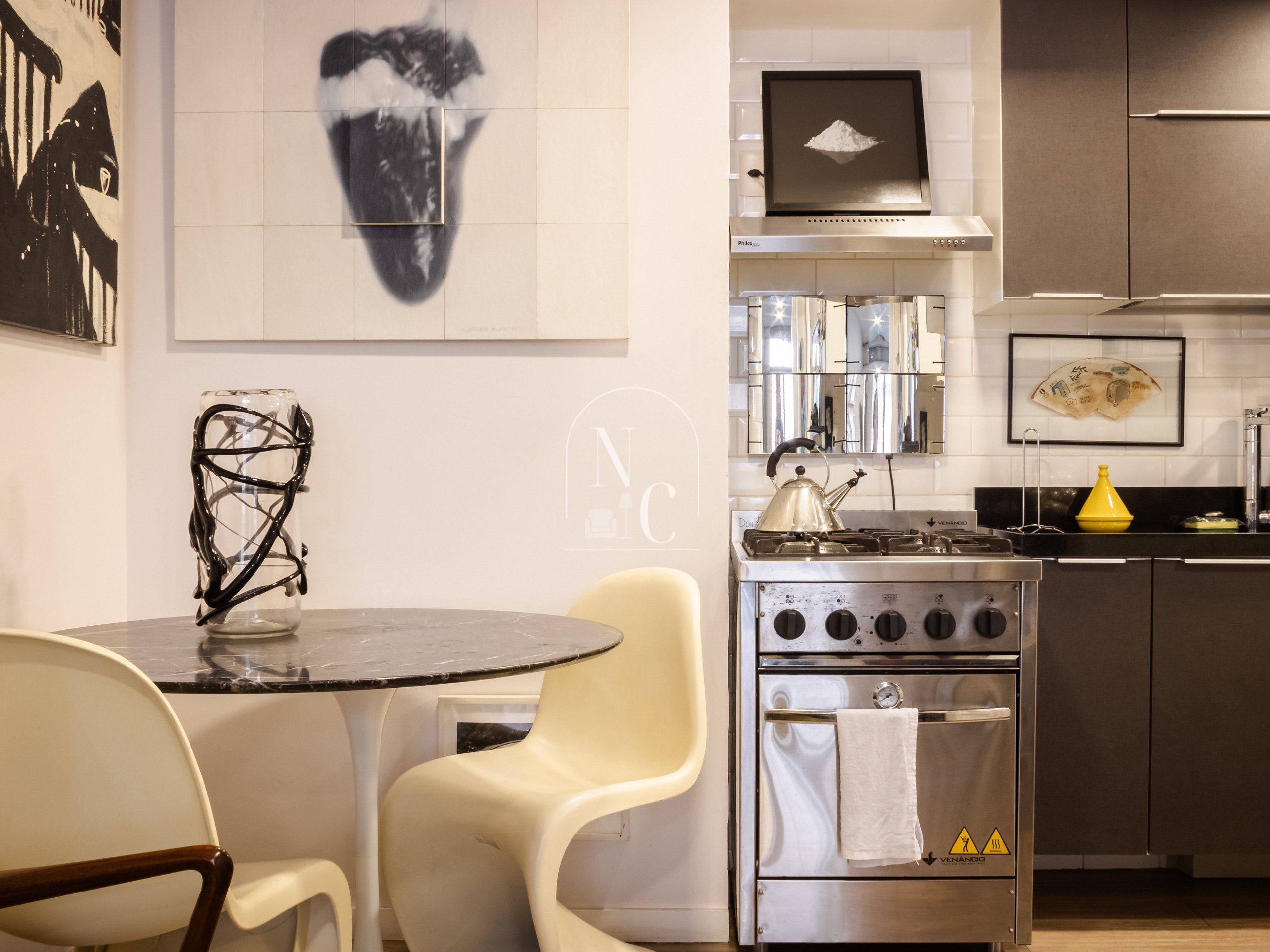 A modern kitchen with a gas stove, stainless steel cabinets, and a dining area with a round table and chairs.