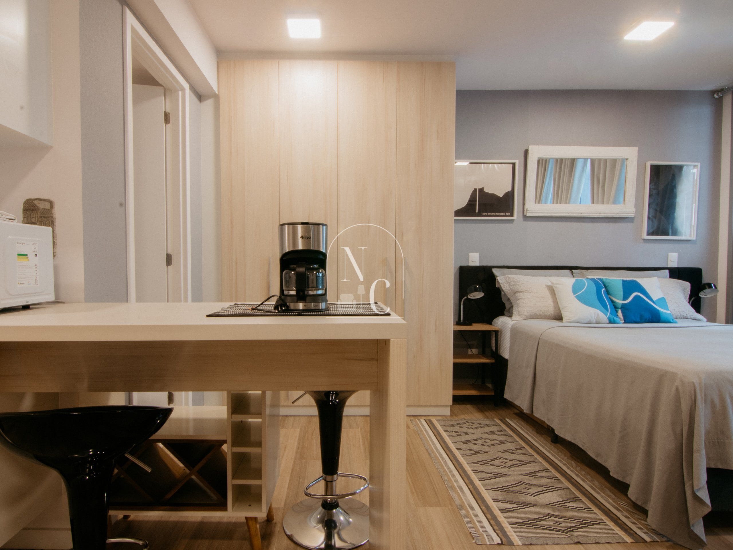 Habitación de hotel con cama, cafetera, escritorio y silla.