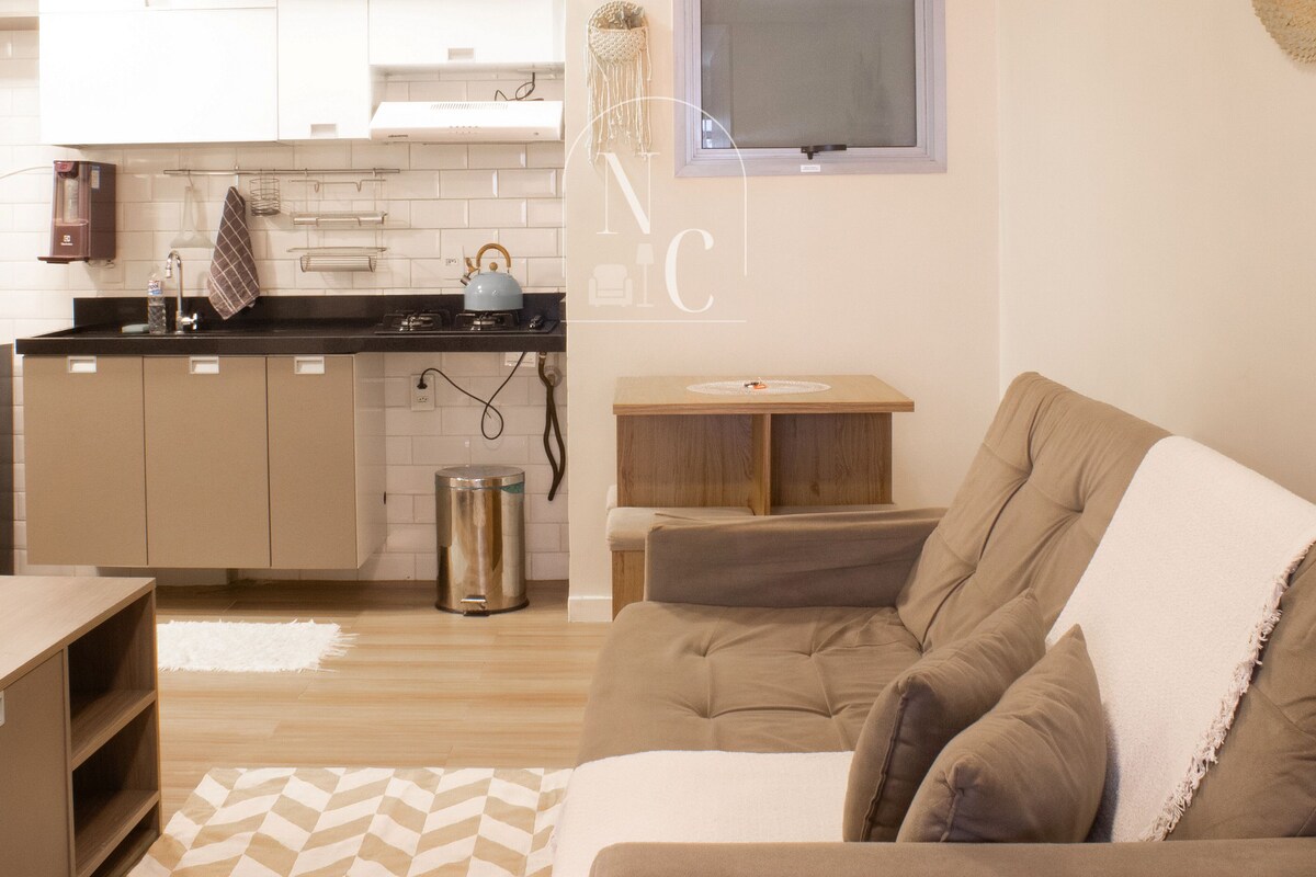 Un espacio habitable pequeño con kitchenette, un sofá y una mesa.