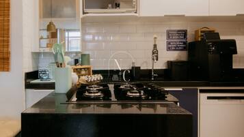 Een keuken met een inbouwmagnetron, een koffiezetapparaat en een spoelbak.