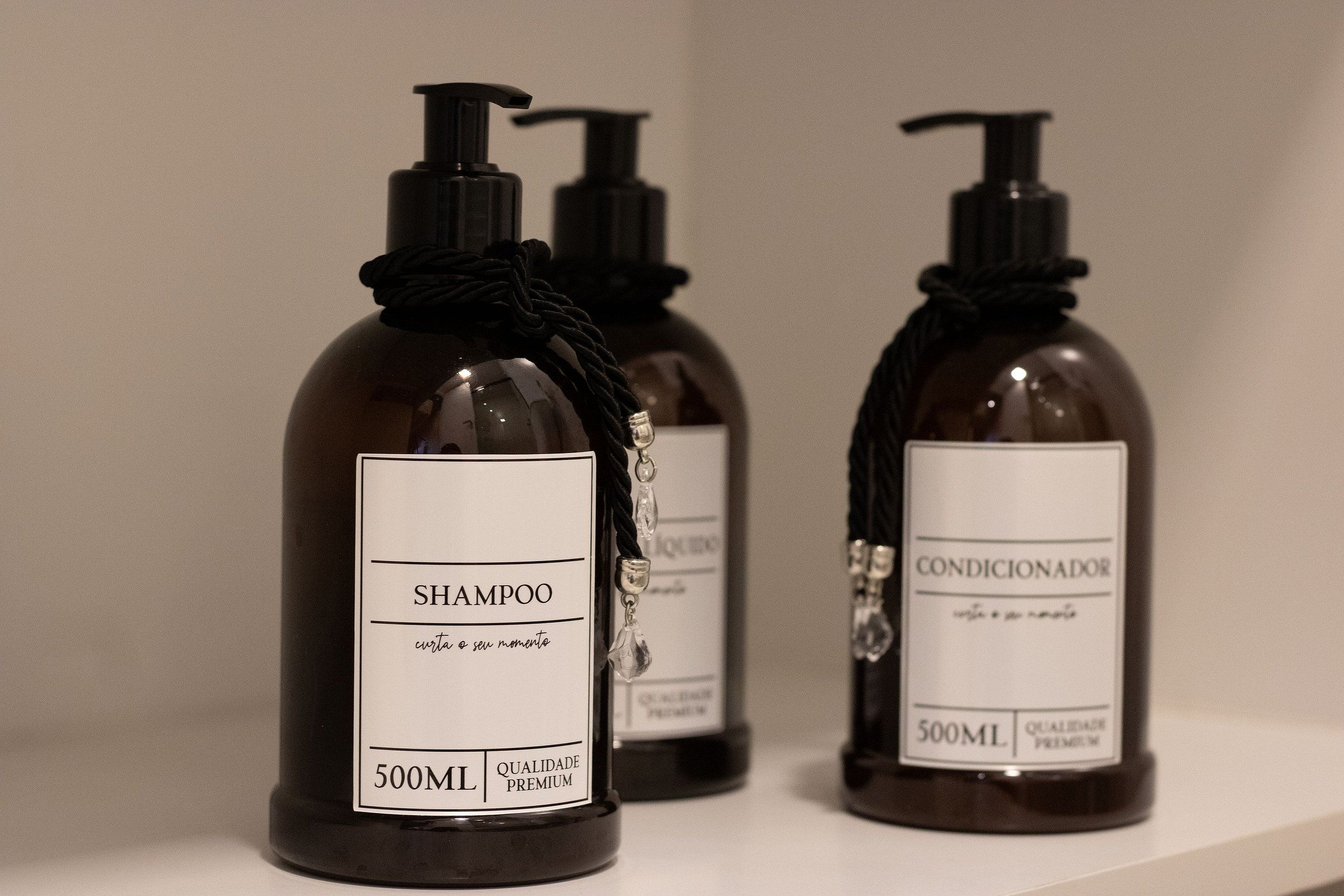Three bottles of shampoo and conditioner on a shelf.