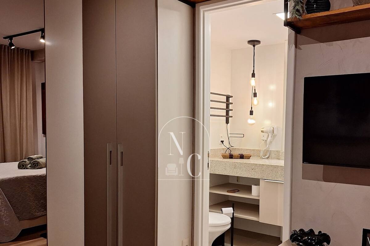 Quarto moderno com guarda-roupa, penteadeira com espelho e televisão na parede.