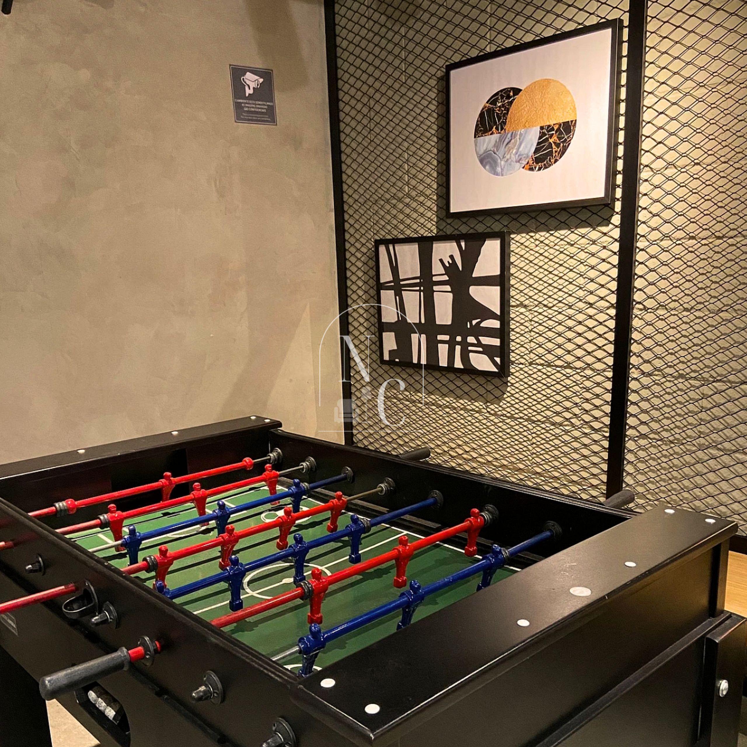 A foosball table in a room with a textured wall and a framed artwork above it.