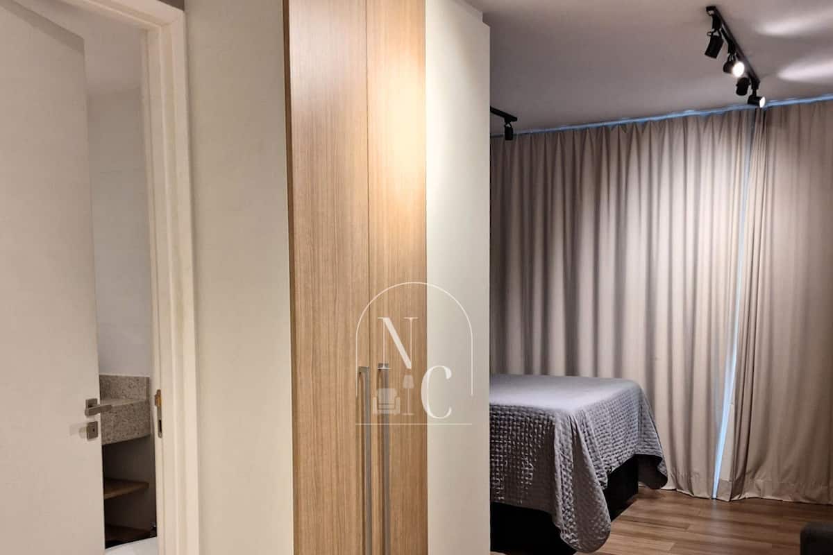 Quarto moderno com um guarda-roupa de madeira, uma cama com colcha cinza e uma cortina.