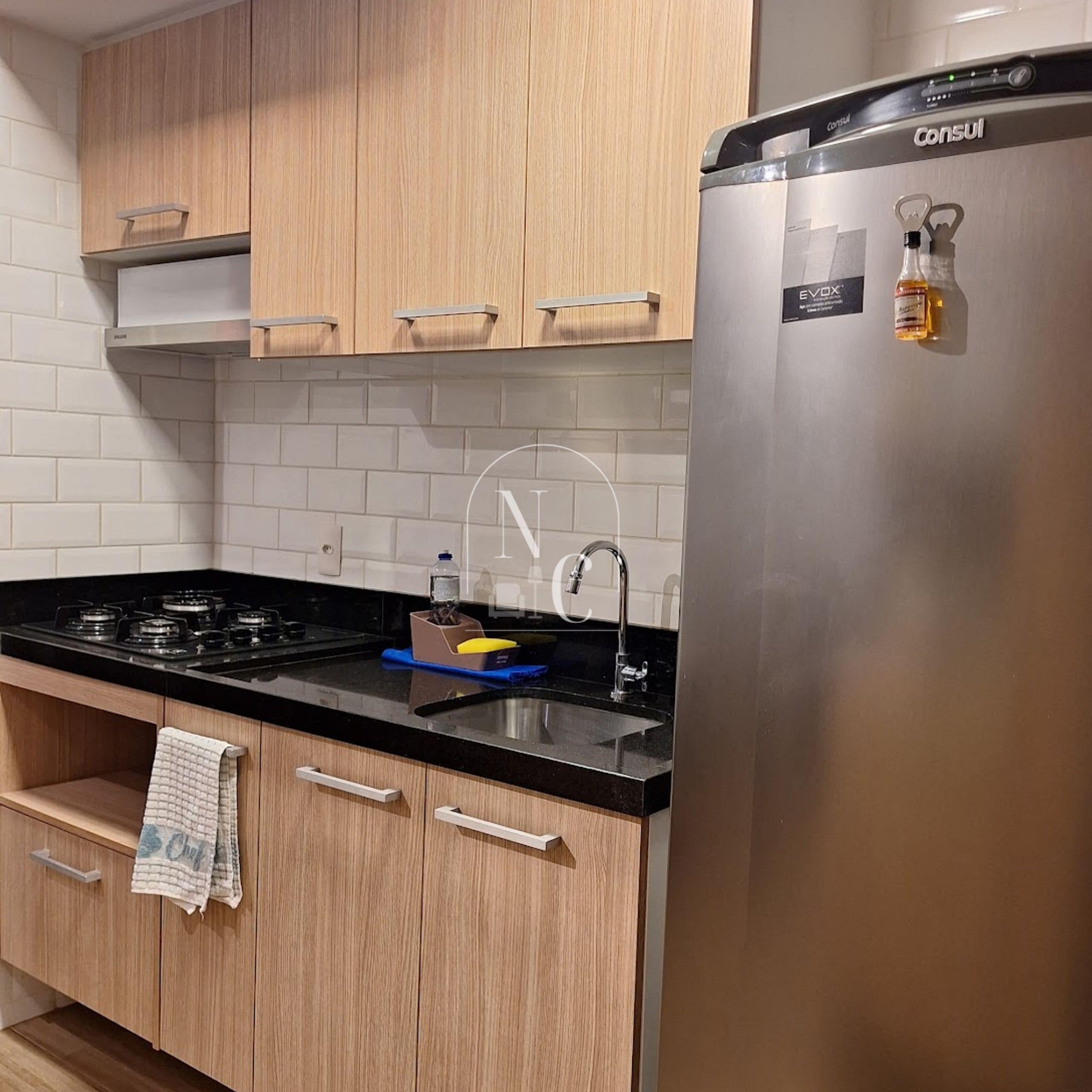 A kitchen with wooden cabinets, a stainless steel refrigerator, a gas stove, and a sink.