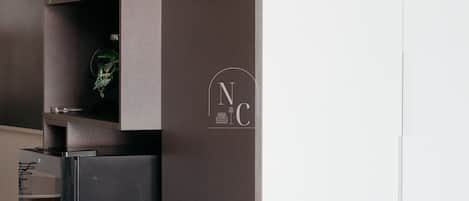 Una cocina moderna con un refrigerador integrado, un estante pequeño con adornos, y un logotipo en la pared.