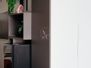 A modern kitchen with a built-in refrigerator, a small shelf with decorative items, and a logo on the wall. - RioDowntown Hub by RNC Flats (Rio de Janeiro)