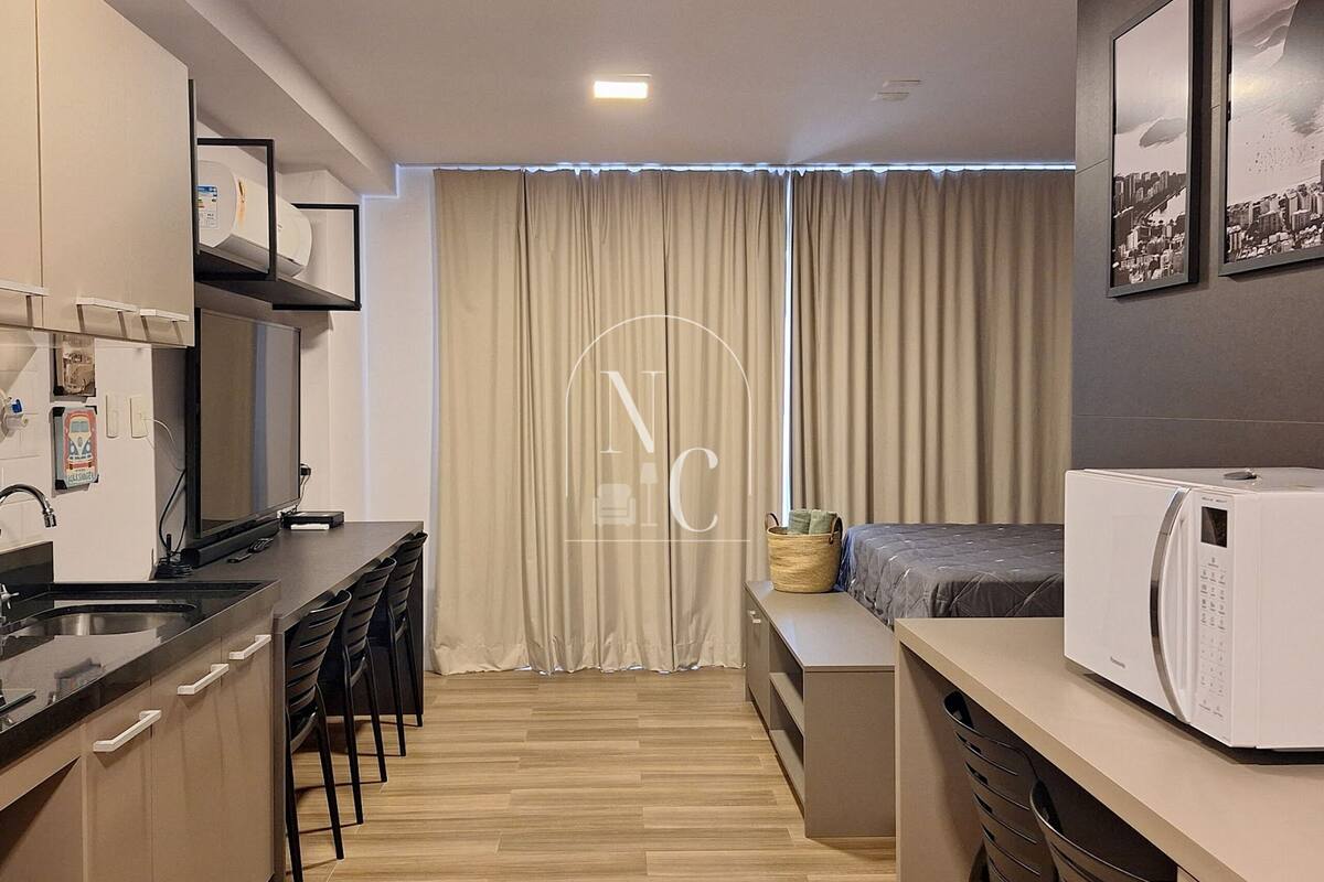 Uma cozinha moderna com área de refeições, micro-ondas e uma janela grande com cortinas.