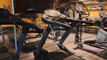 A gym with treadmills, exercise bikes, and a digital clock displaying 15:07.