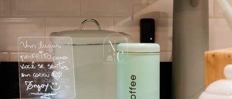 A kitchen counter with a coffee container, a glass jar with a handwritten note, and a white appliance in the background.
