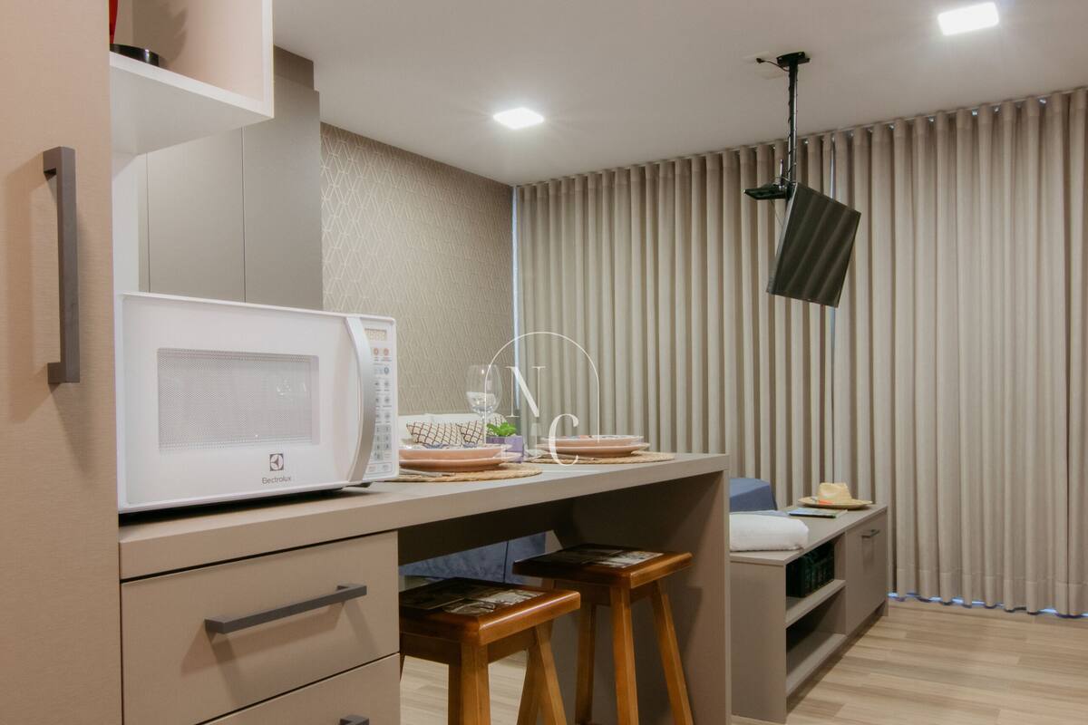 Uma cozinha compacta com micro-ondas, banquetas de bar e um pequeno espaço para sentar.