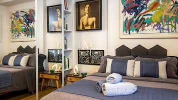 Ein Schlafzimmer mit zwei Betten, Bildern an den Wänden und einem Bücherregal.
