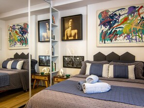 Un dormitorio con dos camas, obras de arte en las paredes y una estantería.