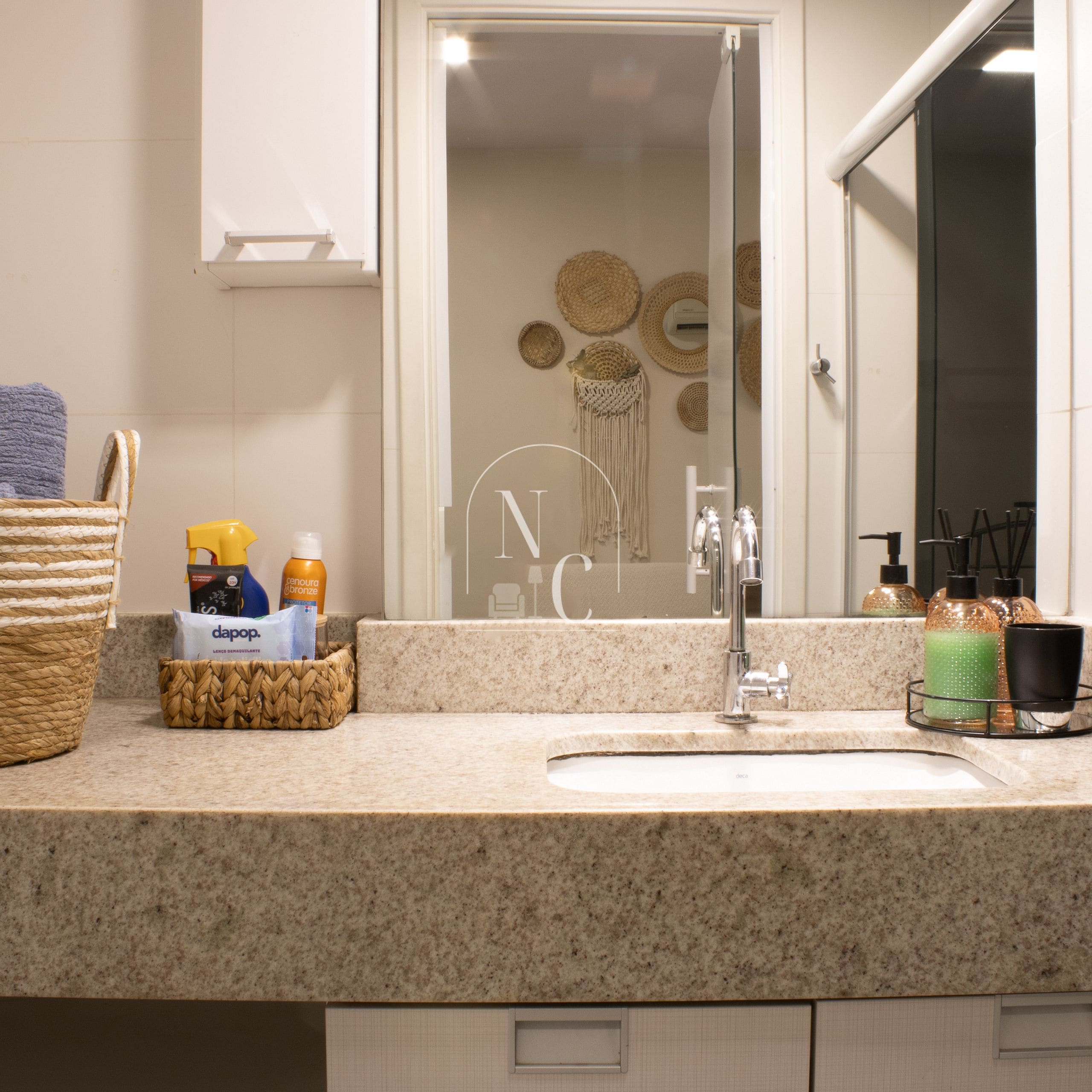 A bathroom with a granite countertop, a glass shower enclosure, and a mirror reflecting a wall with circular wall decor.