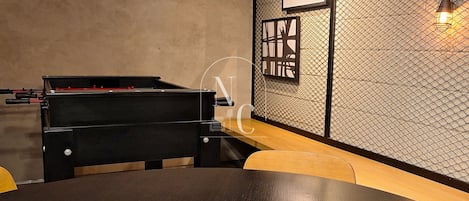 A room with a pool table, a piano, and a round table.