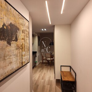 A hallway with a wooden floor, a dining area with chairs, and a wall-mounted artwork. - RioDowntown Hub by RNC Flats (Rio de Janeiro)