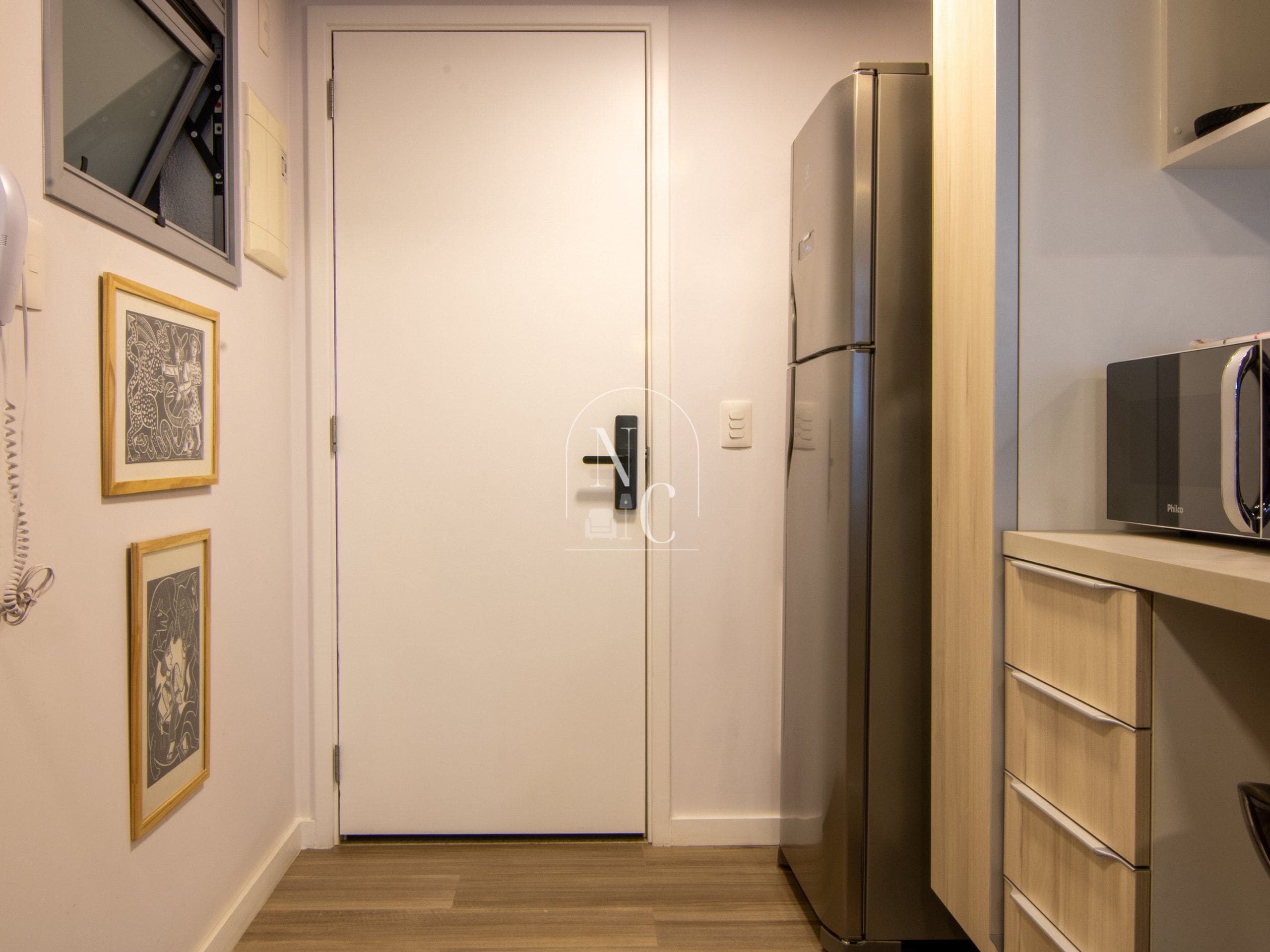 Eine kleine Küche mit Kühlschrank, Mikrowelle und Holzschränken.