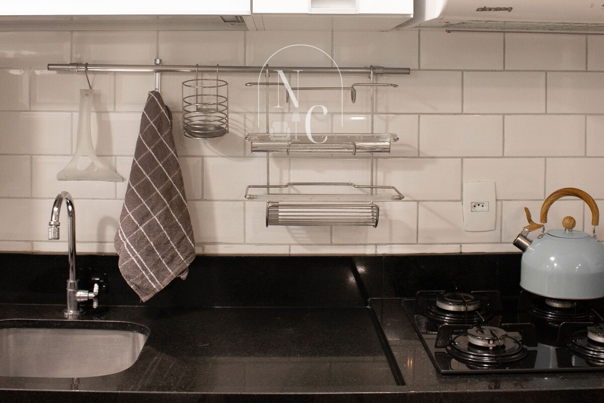 Una cocina con encimera negra, pileta de acero inoxidable y hervidor.