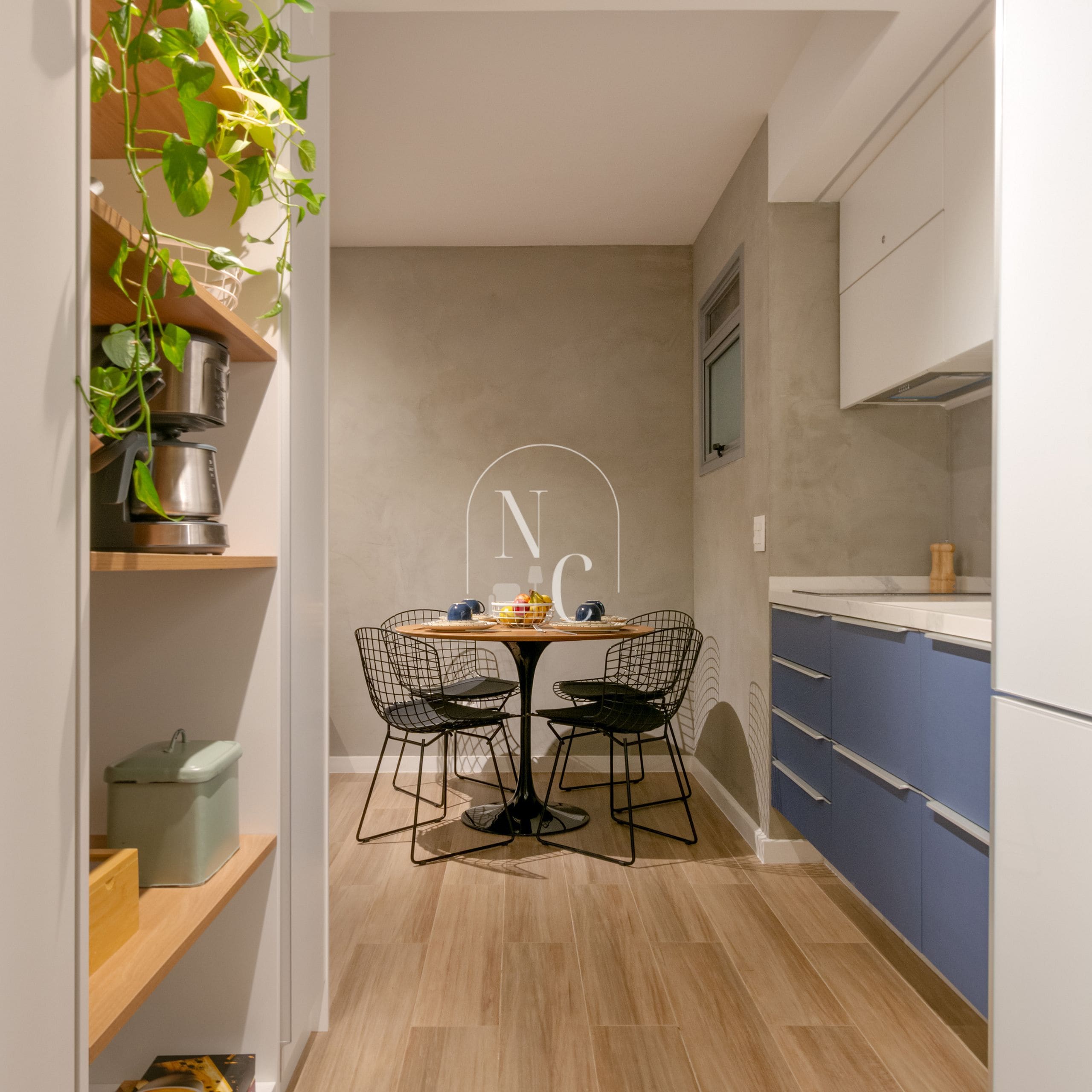 A modern kitchen with a dining table, chairs, and a plant.