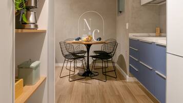 A modern kitchen with a dining table, chairs, and a plant.