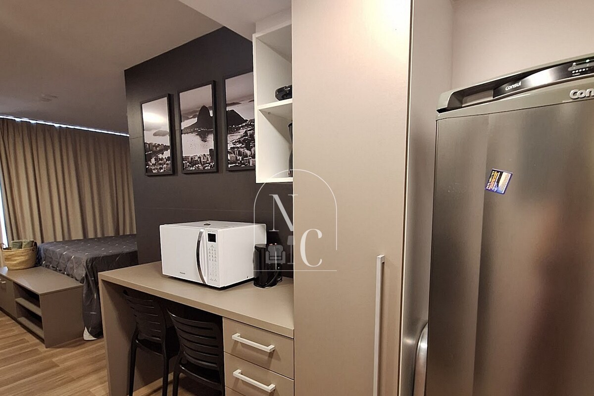 Cocina compacta con refrigerador, microondas y cafetera.