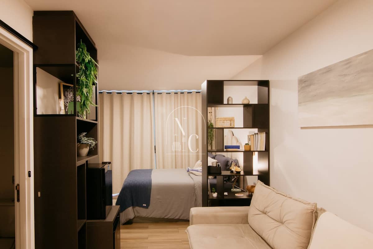 Quarto moderno com cama, sofá, estante e escrivaninha.