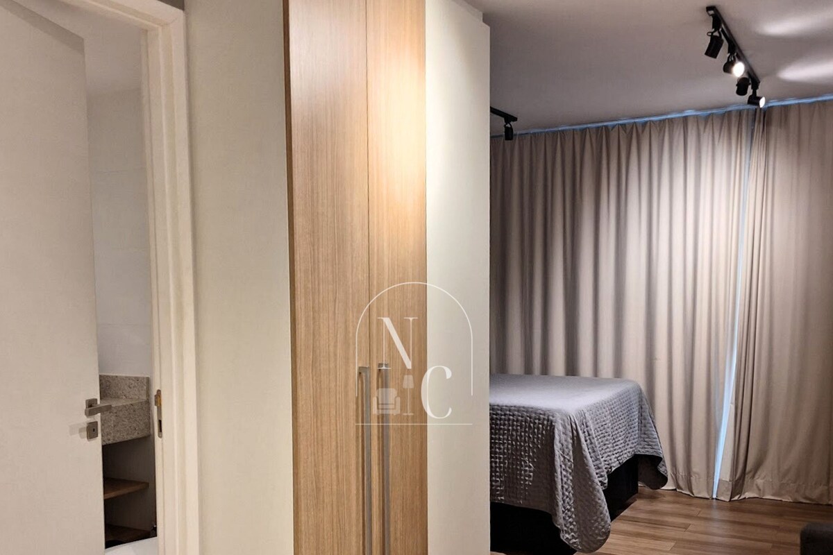 Un dormitorio moderno con un armario de madera, una cama con cubrecama gris y una cortina.