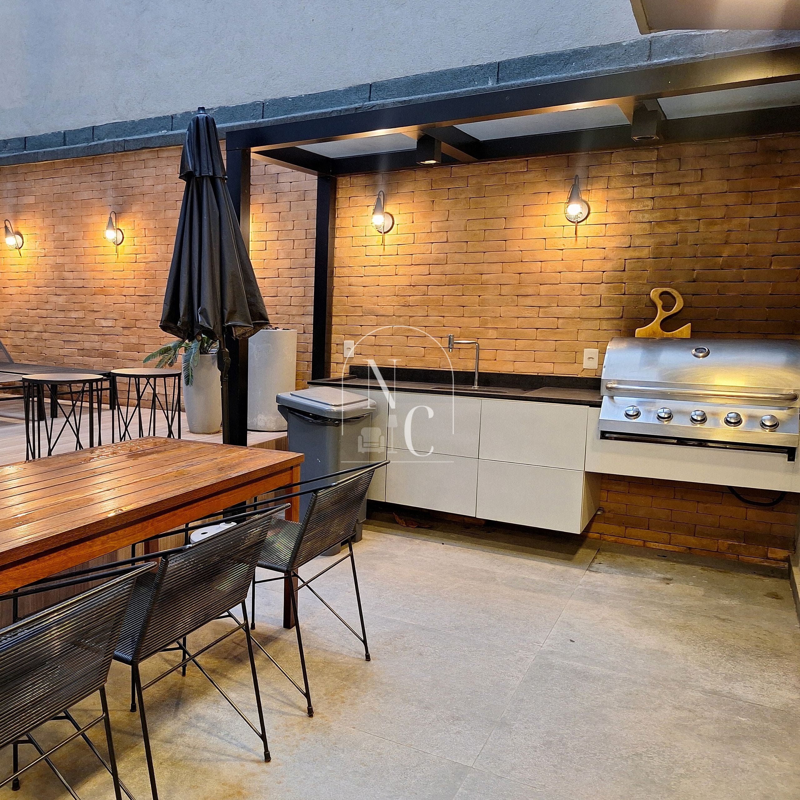 Une cuisine extérieure équipée d’un barbecue, d’une table à manger, de chaises et d’une poubelle.