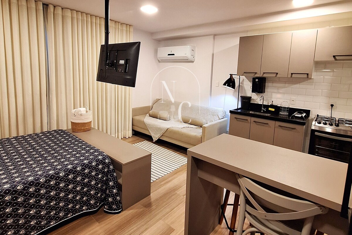Una habitación de hotel compacta con una cama, una kitchenette pequeña, un sofá y un comedor.