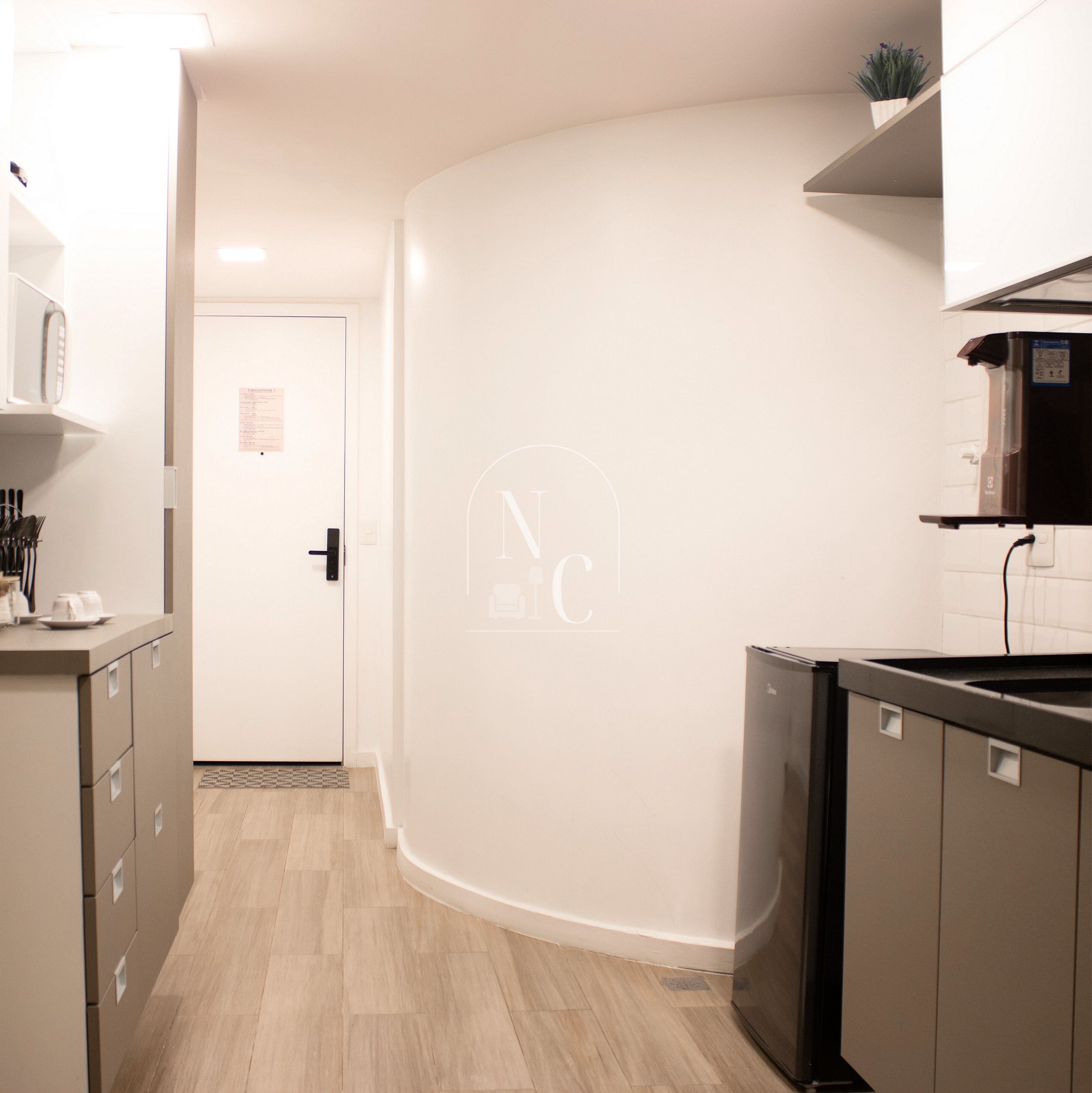 A modern kitchen with a dishwasher, a microwave, and a sink. There is a door leading to another room.