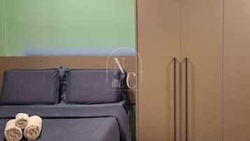 A bedroom with a bed, pillows, a wooden nightstand, and a wardrobe.