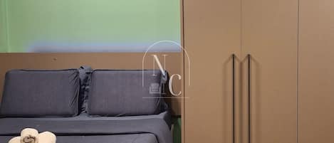 Ein Schlafzimmer mit Bett, Kissen, einem Nachttisch aus Holz und einem Kleiderschrank.