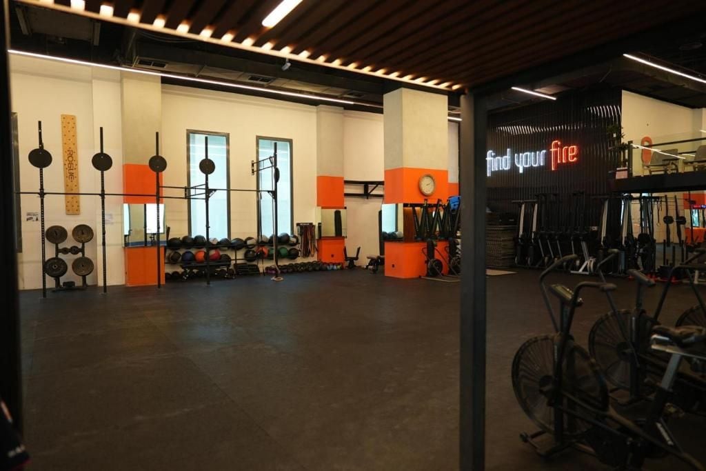 Un gimnasio con equipo de ejercicio, estantes para pesas y un letrero que dice 'find your fire'.