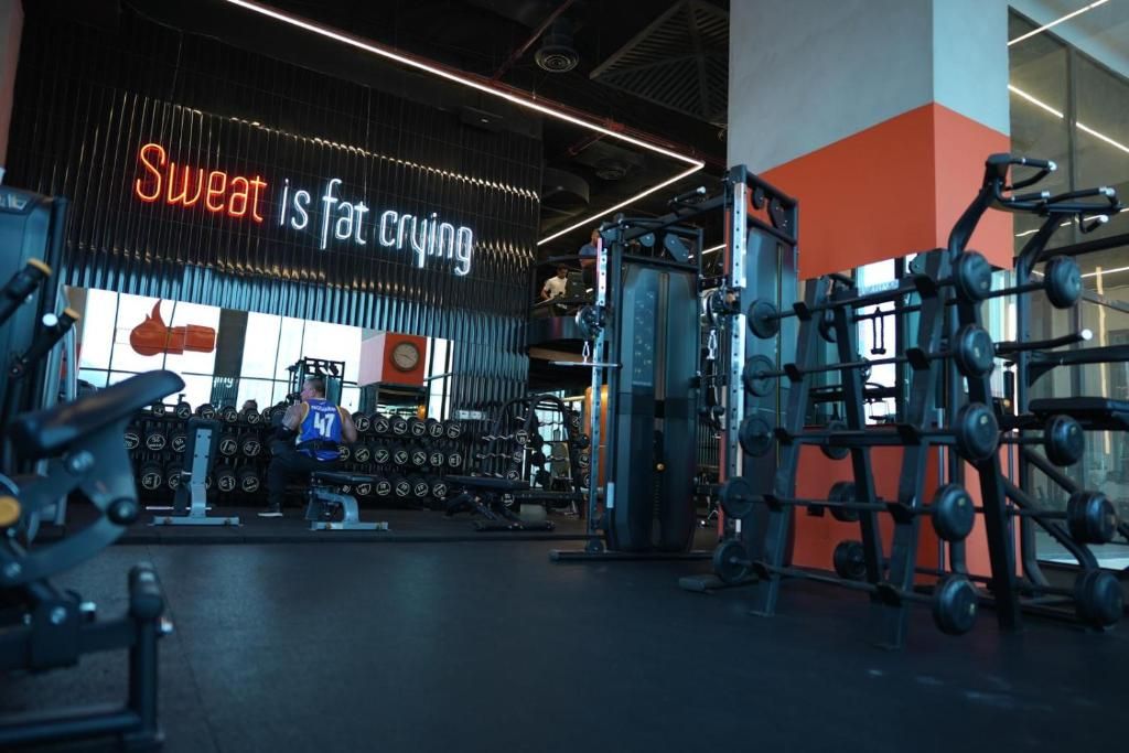 Un gimnasio con equipo de levantamiento de pesas y un letrero motivacional.