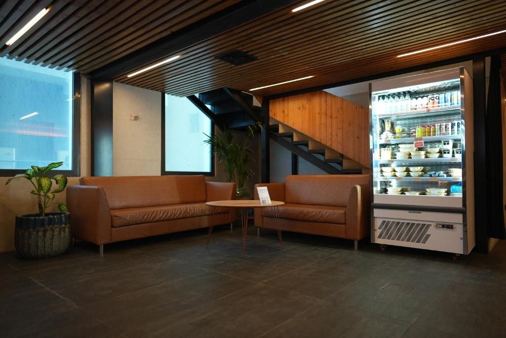 A modern interior with a seating area, a staircase, and a refrigerated display case.
