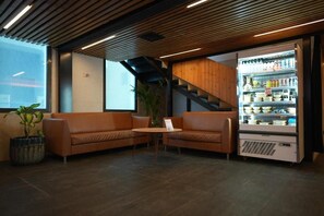 Un interior moderno con una zona de estar, una escalera y un expositor refrigerado.