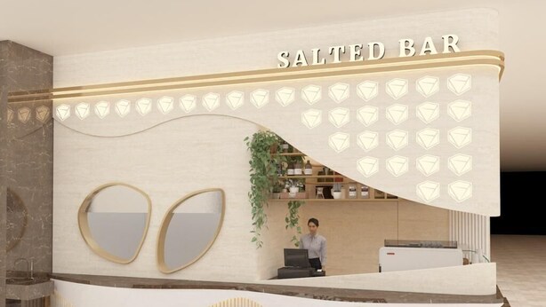 A reception area with a 'Salted Bar' sign, two large mirrors, a plant, and a person at a desk. - Garden Hotel (Jabriya)