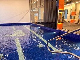 Una piscina interior con agua cristalina, una escalera metálica y un diseño de interiores moderno.
