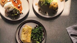 Four plates of food with various dishes, including a piece of meat and vegetables, on a table. - Garden Hotel (Jabriya)