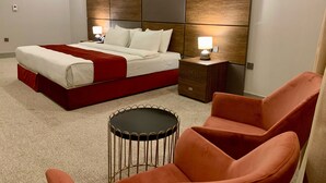 A hotel room with a bed, nightstands, a round table, and a chair. - Garden Hotel (Jabriya)
