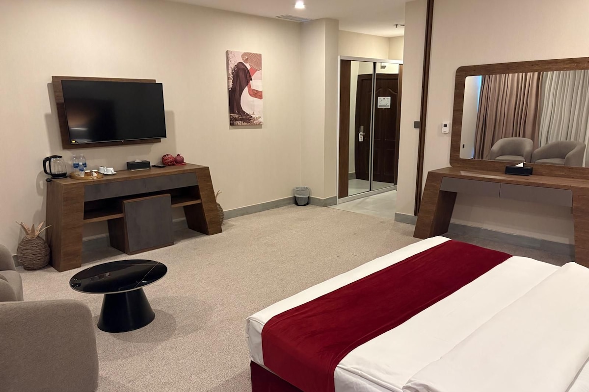 A hotel room with a bed, a desk, a television, and a mirror.