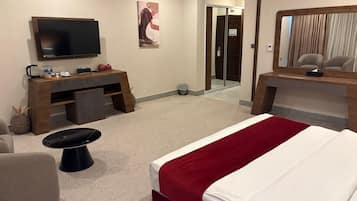 Habitación de hotel con cama, escritorio, televisor y espejo.