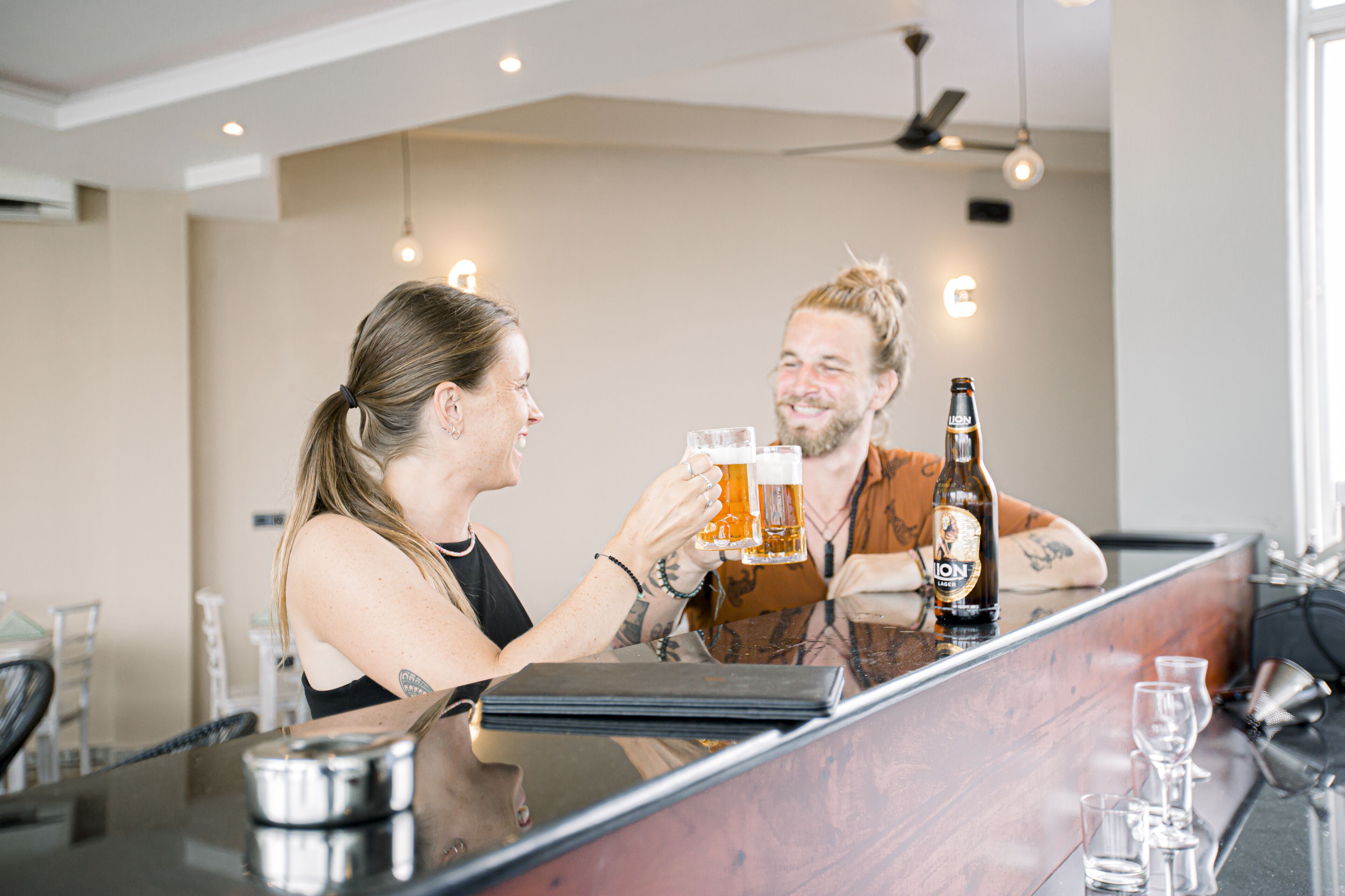 A bar area with a counter, glasses, and a bottle of beer.