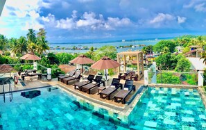 A pool area with lounge chairs and umbrellas, overlooking a marina and coastal view. - Emerald Bay Resort Mirissa (Mirissa)