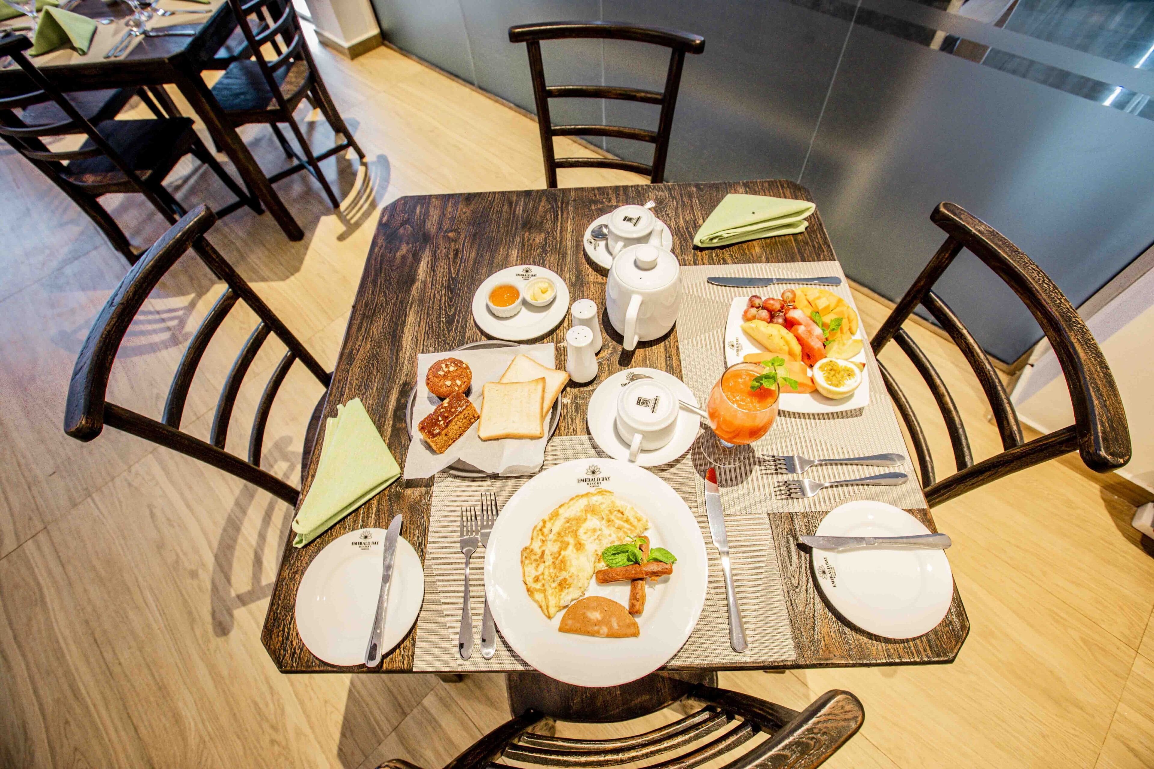 Une table à manger dressée avec des assiettes, des couverts et différents plats, entourée de chaises.