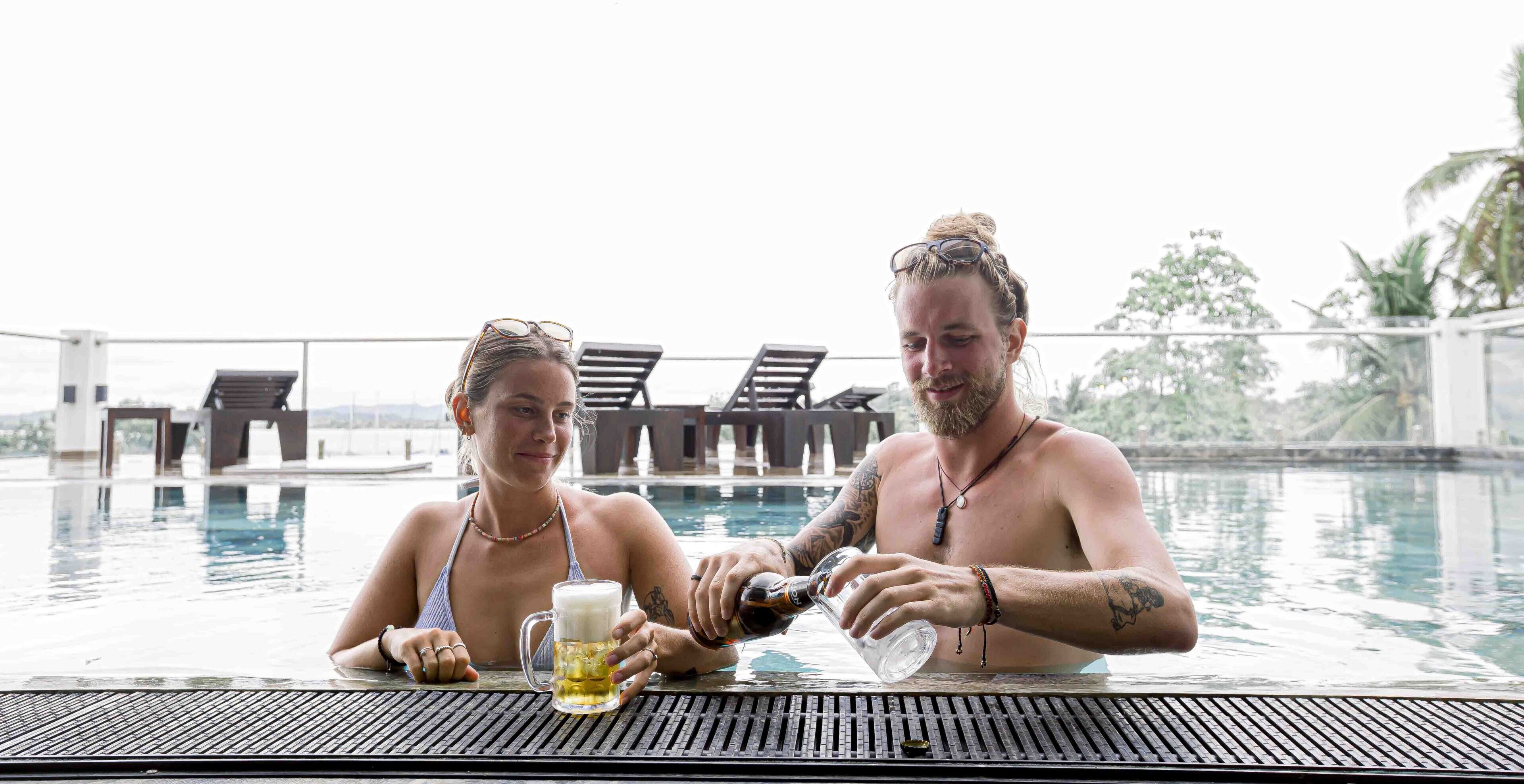 Dos personas en un entorno de piscina con una mesa y sillas.