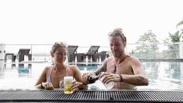 Dos personas en un entorno de piscina con una mesa y sillas.