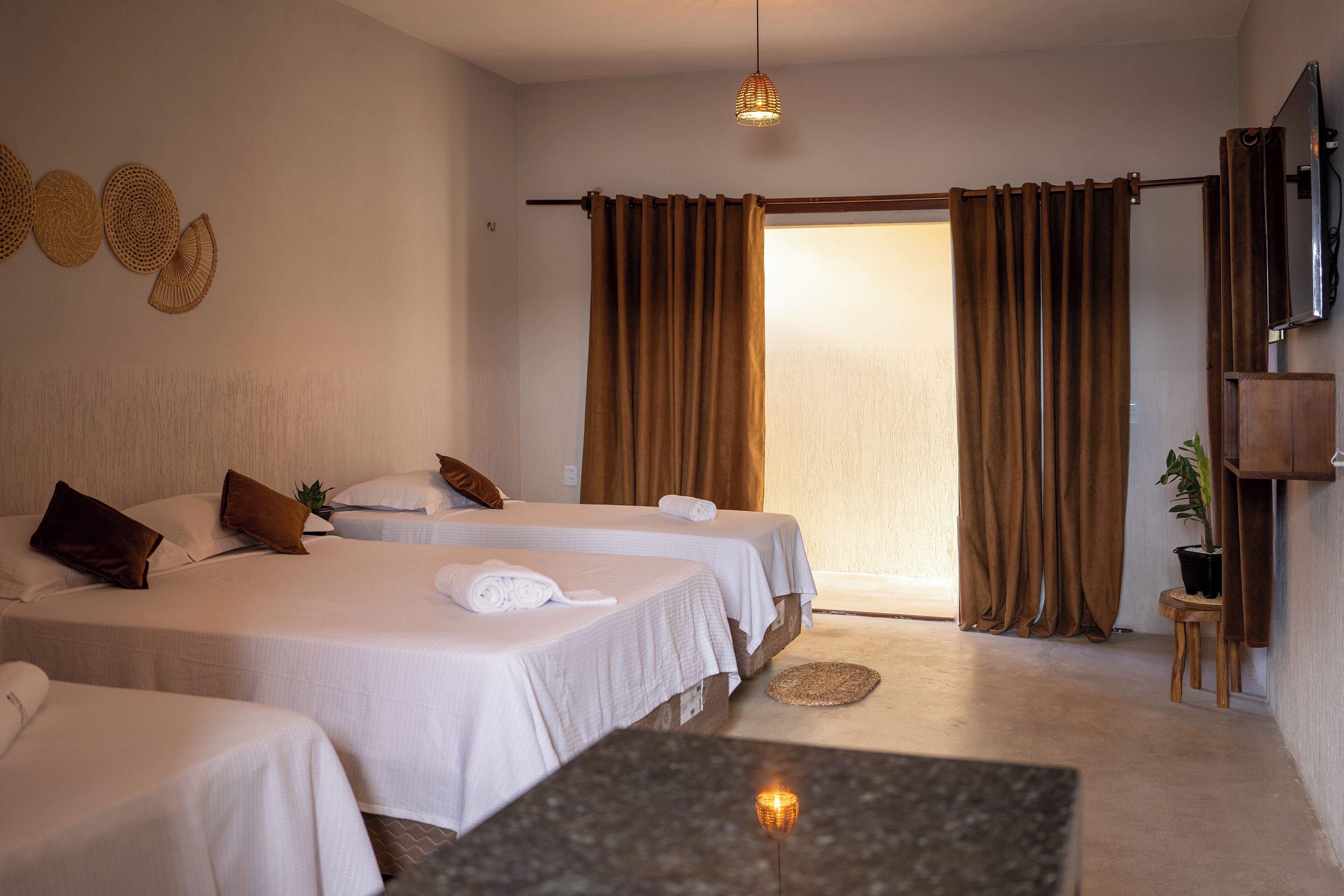 Habitación de hotel con dos camas, una mesita, un televisor y una puerta que da a un balcón.