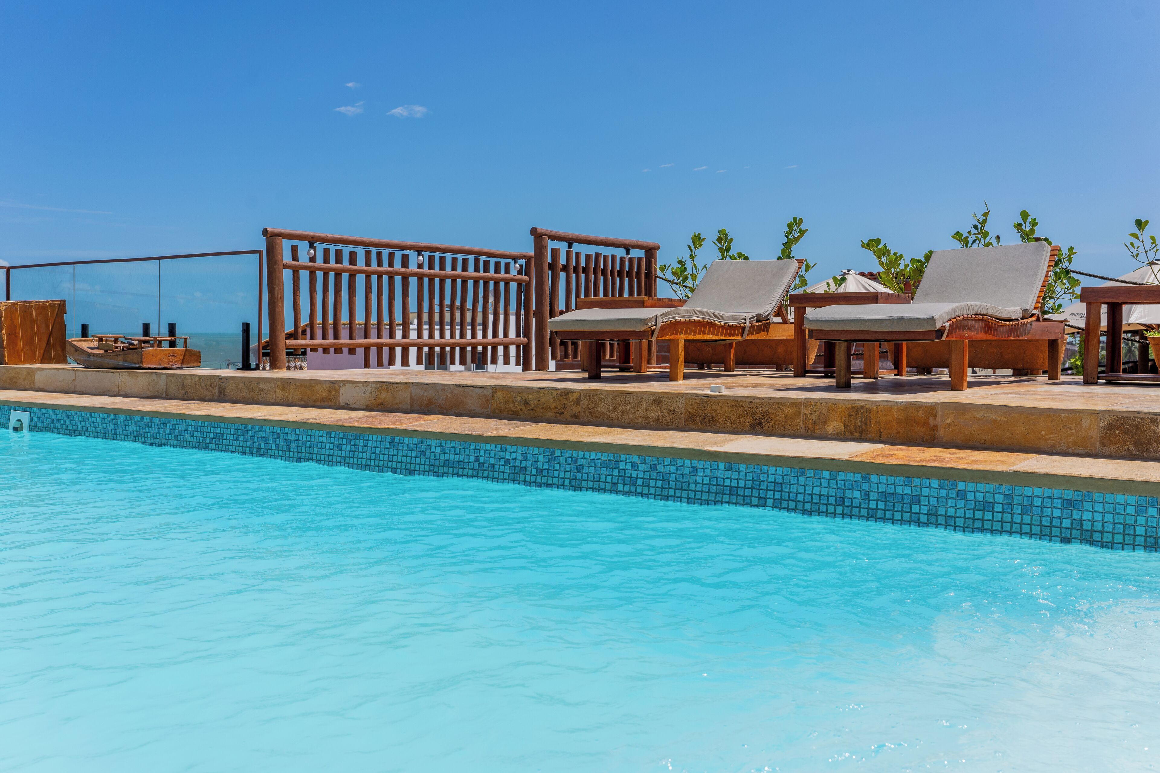 A poolside area with lounge chairs and a wooden fence.